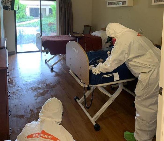 Two employees of SERVPRO cleaning a room with hospital beds. 
