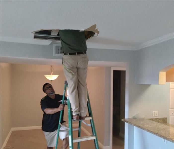 tech on ladder looking into ceiling water damage