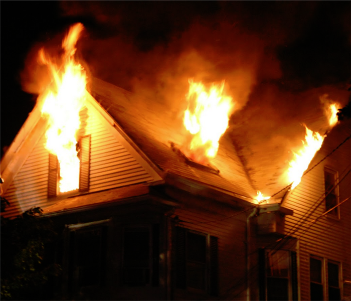 fire on second floor of a house with flames coming out of the windows